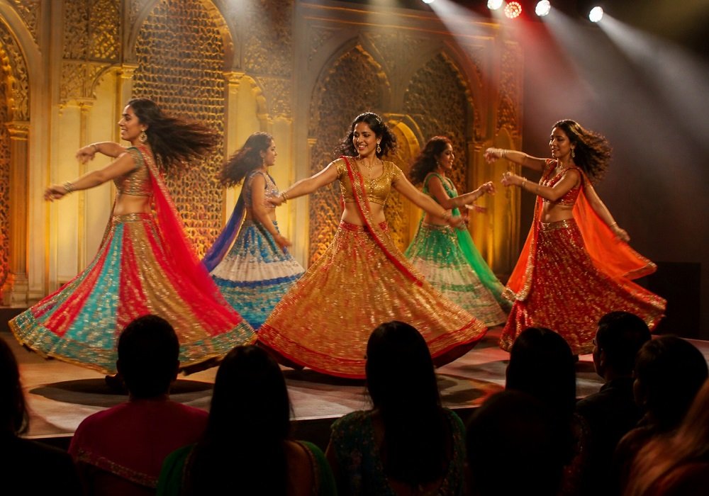 Dancers performing on a Bollywood theme stage with gold arch backdrop