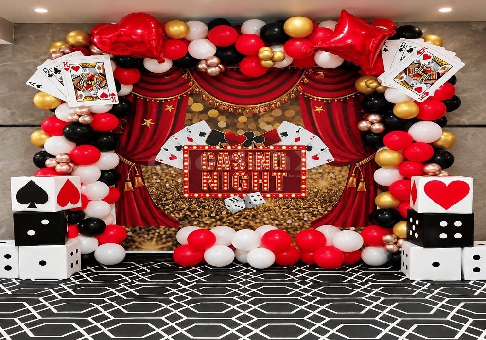 Casino night party setup with a marquee backdrop, balloon arch, oversized playing cards and dice