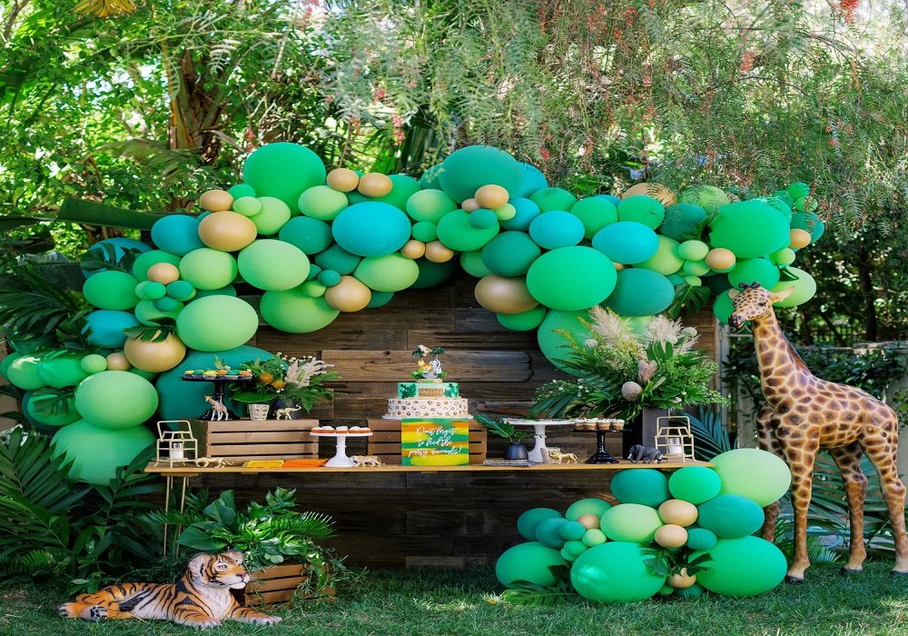 Jungle theme party setup with lush green foliage, hanging vines and animal props
